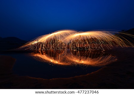 fire Steel wool on river at night, Showers of glowing sparks from spinning steel wool