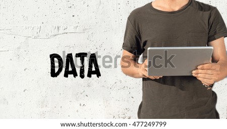 Young man using tablet pc and DATA concept on wall background