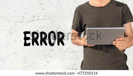 Young man using tablet pc and ERROR concept on wall background