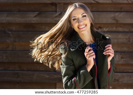 Pretty girl with flying hair near wooden wall