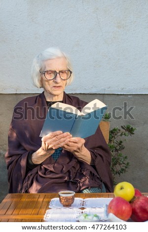 Senior woman reading a blue book outdoors