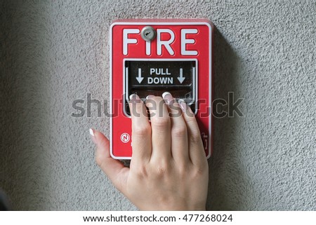 Hand pulling down the fire alarm button
