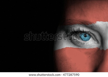 A young female with the flag of Austria painted on her face on her way to a sporting event to show her support.