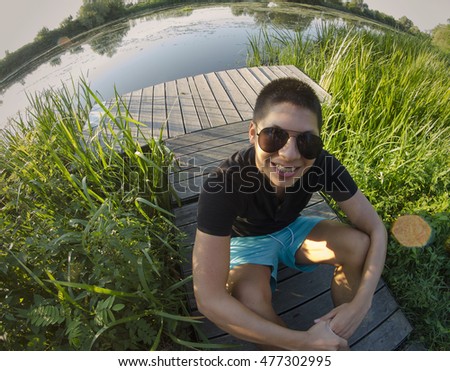 Happy vietnamese guy at the lake in summer with fish eye lens