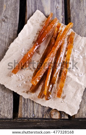 Thin sticks of smoked fish on the wooden background. Selective focus.