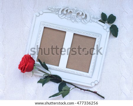 Wooden retro photo frame and red rose on knitted background.