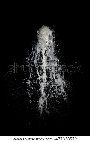 Water being forced into the air in front of a black background. Royalty-Free Stock Photo #477338572