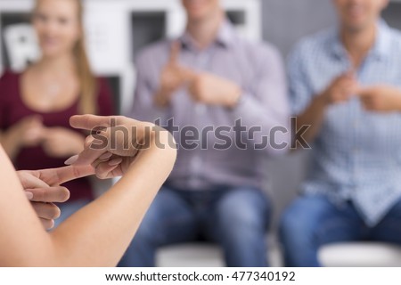Close up of hands in to gossip gesture, in the background blurred image of three people Royalty-Free Stock Photo #477340192