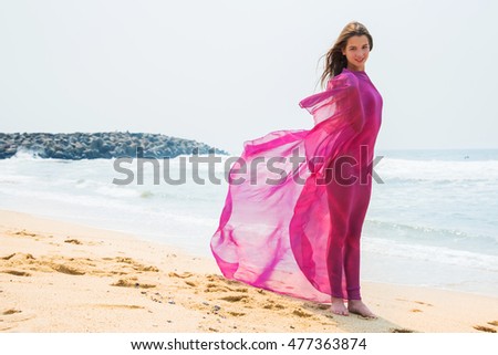 Sport girl-teenager in a pink bathing suit on background of ocean.