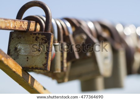 Closeup of many love locks on iron fence on the blue sky background. Locks of love - symbol of lovers. Selective focus.