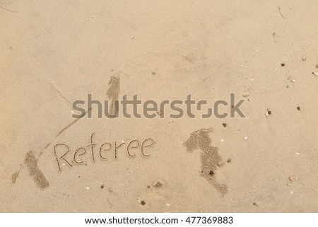written words "Referee" on sand of beach