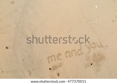 written words "me and you" on sand of beach