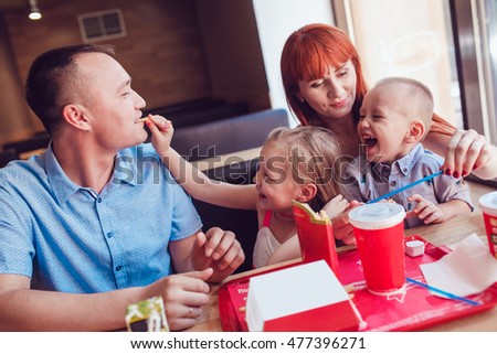 Happy family eating fast food in restaurant all together Royalty-Free Stock Photo #477396271