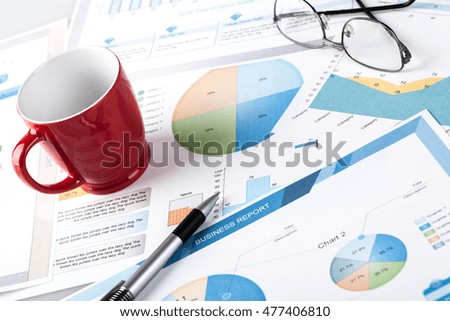 Pen on document with charts and coffee