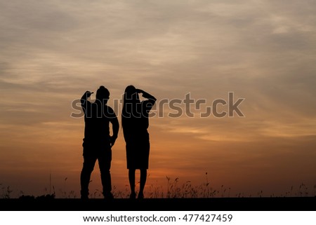 Silhouette man and woman with beautiful the sky at sunset.
Background, he and she inside sweetheart