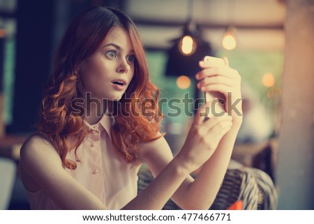
woman with a phone in a restaurant photographed themselves on the phone surprised