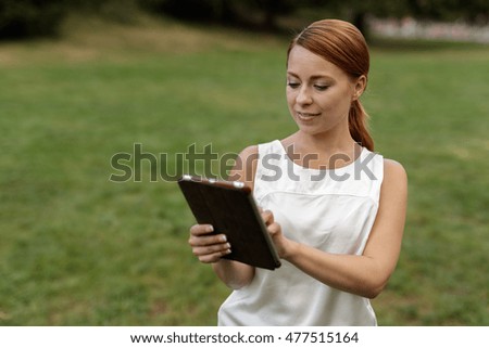 Woman in a park using tablet computer
