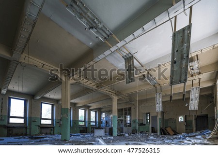 Destroyed interior of factory hall with great mass contains money things around on the floor. Creative compose photography by using wide angle tilt shift lens.
