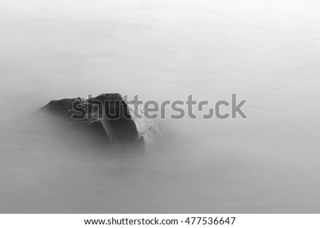 Dark rock in the sea . Long exposure photography  for smooth water level and dreamy effect