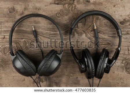 Two headphones and the cord symbolic of a love for music on an antique wooden texture background, top view