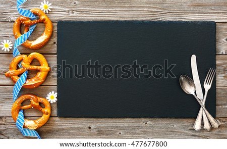 Bavarian pretzels with silverware on wooden board. Background for Oktoberfest
