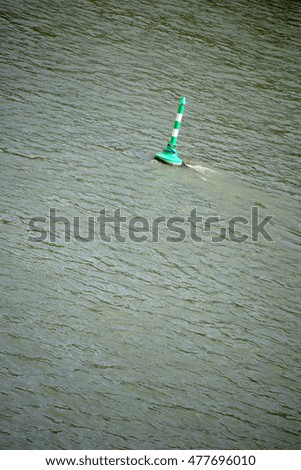 A green and white striped buoy on a river near an inland port / Signal buoy                          