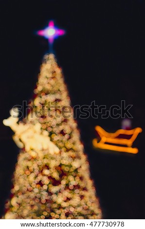 Christmas background. Blurred image of Christmas tree, reindeer and a sleigh made of lights. Toned image.