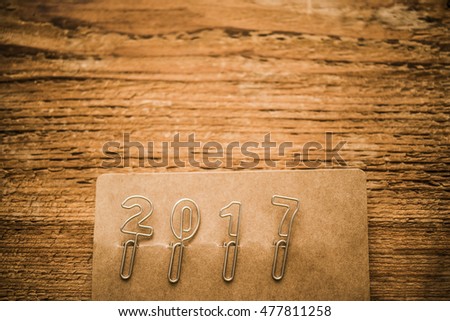 Happy new year 2017 made from new metal paper clips, lie on brown paper and wooden background, retro style