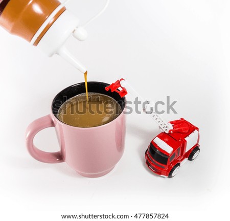 Caramel flavored coffee mix hot pink in the glass with a toy fire truck. Isolated on a white background. 