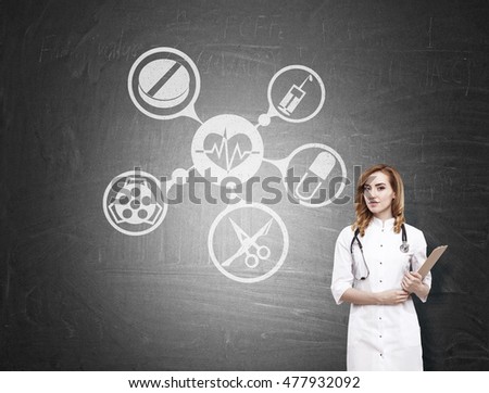 Portrait of gorgeous woman doctor with stethoscope and clipboard standing near blackboard with medical icons on it. Concept of medical education