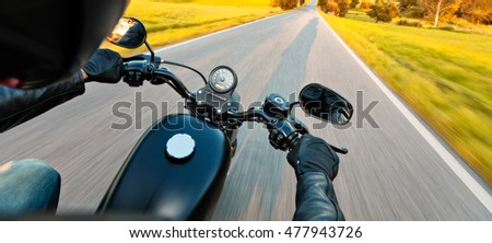 Motorcycle driver riding on motorway in beautiful sunset light. Shot from pillion driver view Royalty-Free Stock Photo #477943726