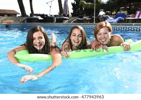 group of three happy and beautiful young girl friends having bath floating in airbed in swimming pool together having fun enjoying summer at vacation resort smiling in women holiday concept