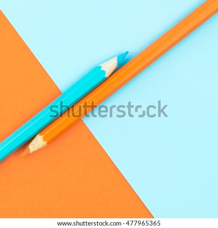 Orange and Turquoise coloured pencils and paper, abstract contrast conceptual image