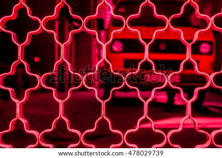 red ornament grid on dark background with big car, red netting against dark back, netting grid as texture, high quality resolution