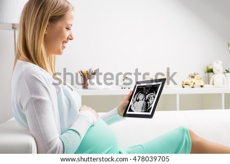 Pregnant woman using tablet to look at sonogram results
