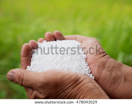 urea fertilizer,farmer hand holding plant chemical fertilizer over green background