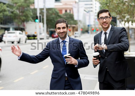 Two young businessmen hailing for a taxi