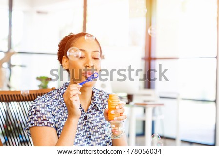 Portrait of smiling afro-american office worker blowing bubbles