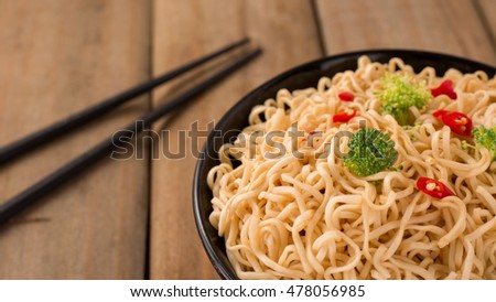 Instant noodles with vegetables in a bowl on wood background.