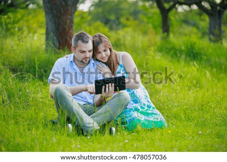 Happy pregnant couple with tablet