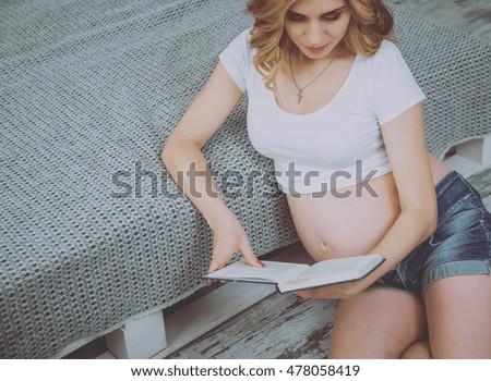 Young pregnant woman reading a book