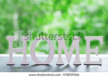 The word Home on wooden table with green natural background
