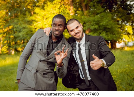 Two young businessman in park. Beautiful background.