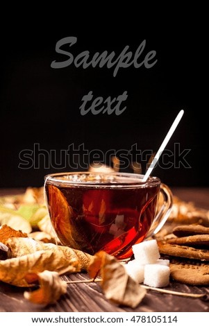black hot tea with autumn leaves on a brown wooden table