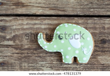 Homemade gingerbread cookie in the shape of green elephant with polka dots on a wooden background. Space for text and selective focus.
