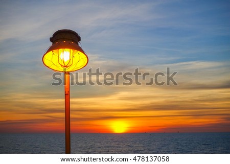 Lighting of warm lamp or yellow HID lamp and lighting of sunset at sea with beautiful sky and clouds in the evening with twilight time on offshore platform.