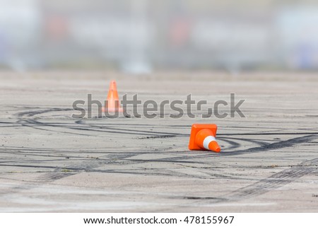 Signal cone orange on the race track-grey with tire tracks. Cone fell on the track.