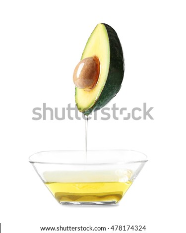 Avocado and bowl with avocado oil on white background.