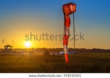 Airfield sign of the direction and force of the wind against sunset sky. Airdrome scene.