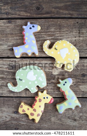 Homemade gingerbread cookie in the shape of green, red and yellow elephants and giraffes on a wooden background. Space for text and selective focus.
